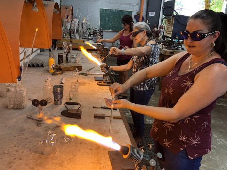 A group of women working with glass in a workshop.